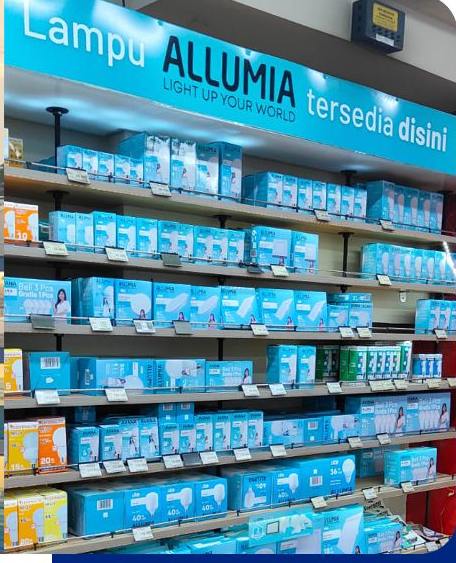 Rak penuh kardus lampu AVANA dan ALLUMIA di toko listrik